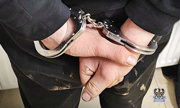 kajdanki na trzymanych z tyłu rękach mężczyzny