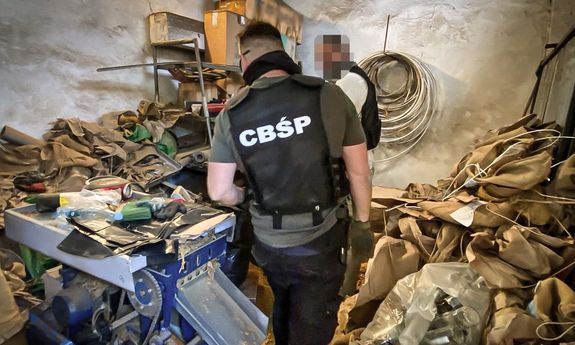 policjant CBŚP stoi na środku pokoju z nielegalną krajanką tytoniową
