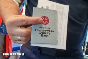 policjant trzyma książeczkę honorowego dawcy krwi