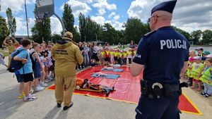 Policjant i strażak rozmawiają z grupą dzieci.