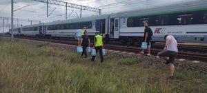 policjanci niosą wodę dla pasażerów pociągu