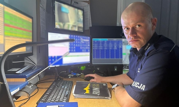 na zdjęciu umundurowany policjant siedzący za biurkiem