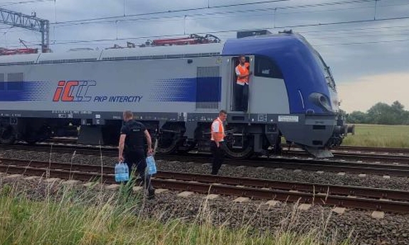 policjanci niosą wodę dla pasażerów pociągu