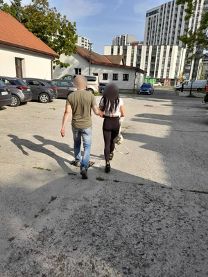 zatrzymana kobieta prowadzona przez nieumundurowanego policjanta