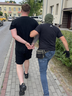 nieumundurowany policjant idzie z zatrzymanym mężczyzną