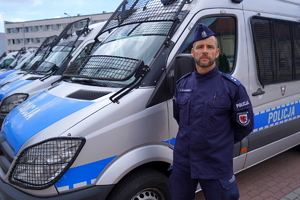 umundurowany policjant stoi przed radiowozem