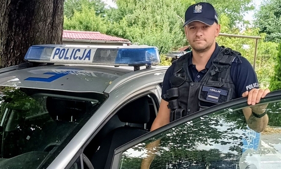 policjant stoi przy radiowozie