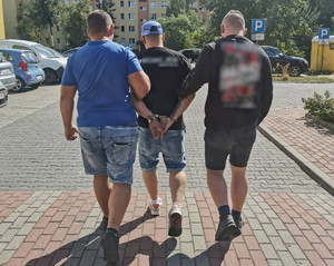 policjanci idą z zatrzymanym