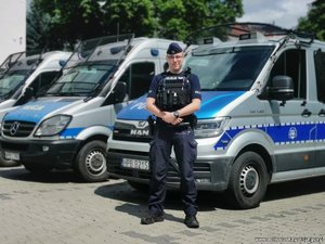policjant stoi przed radiowozem policyjnym