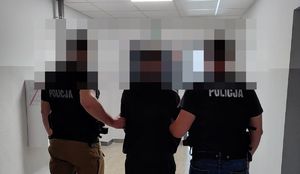 policjanci prowadzą zatrzymanego z kajdankami założonymi na ręce