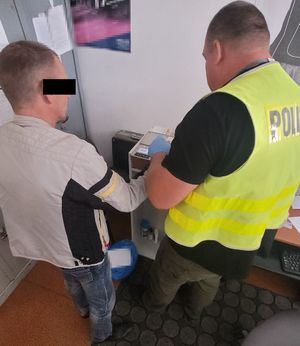 policjant pobiera odciski palców od zatrzymanego mężczyzny