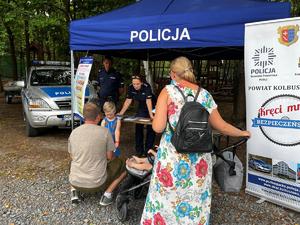 Policjanci przy stoisku profilaktycznym rozmawiają z uczestnikami spotkania.