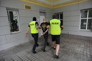policjanci prowadzą zatrzymanego mężczyznę
