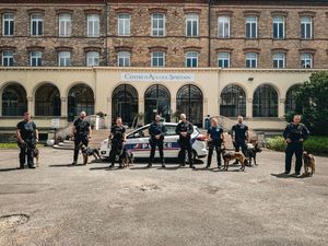 przewodnicy psów służbowych ze swoimi podopiecznymi przed budynkiem