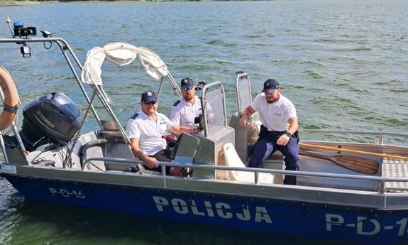 trzech policjantów na łodzi motorowej ubranych w mundury- białe koszulki z napisem Policja i spodnie