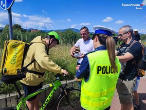 policjantka w odblaskowej kamizelce i stojący obok rowerzysta