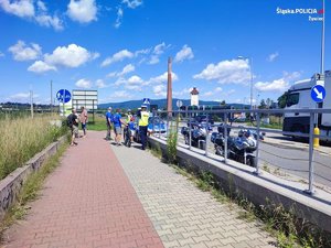 policjant przy trasie rowerowej oraz zaparkowane motocykle policyjne i radiowóz