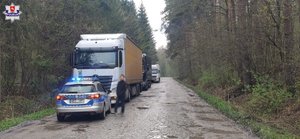 radiowóz  z włączonymi migającymi światłami  niebieskimi i trzy ciężarówki
