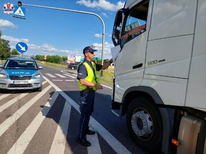 policjant kontrolujący ciężarówkę w tle radiowóz