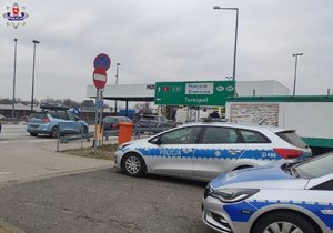 na pierwszym planie dwa radiowozy i widoczna za nimi tablica informacyjna wskazująca przejście graniczne