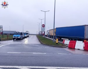 ciąg radiowozów i stojący ciąg ciężarówek w przecinwym kierunku