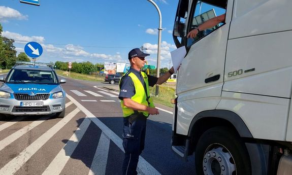 policjant kontrolujący ciężarówkę w tle radiowóz