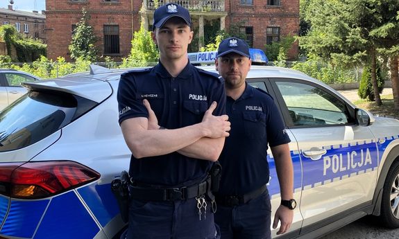 policjanci stoją przed radiowozem