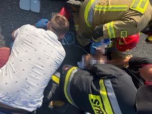 Na zdjęciu strażacy i policjanci pochyleni nad leżącym mężczyzną podpiętym do sprzętu medycznego