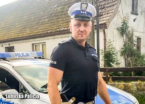 policjant stoi przy radiowozie policyjnym