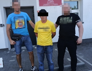 dwaj nieumundurowani funkcjonariusze z zatrzymanym w kajdankach