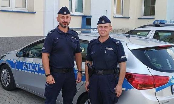 policjanci stoją przy radiowozie