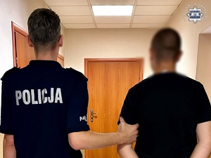 na zdjęciu umundurowany policjant prowadzi zatrzymanego nastolatka