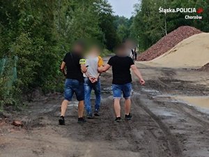 na zdjęciu dwóch policjantów prowadzi zatrzymanego mężczyznę
