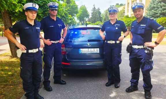 4 policjantów stoi przy radiowozie
