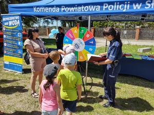 Policjantka podczas gry z grupą dzieci w tle namiot profilaktyczny.