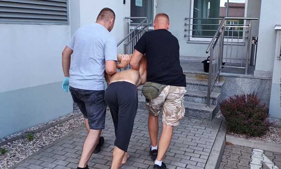 policjanci po cywilnemu prowadzą zatrzymanego mężczyznę zakutego w kajdanki