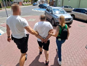 policjant i policjantka prowadzą zatrzymanego mężczyznę