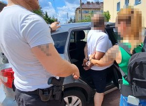 policjant i policjantka prowadzą zatrzymanego mężczyznę