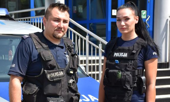 policjanci stoją przed radiowozem