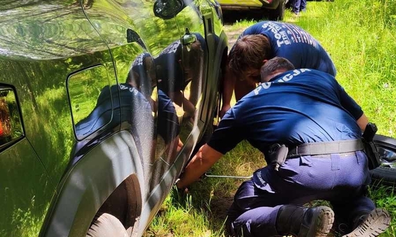 na zdjęciu dwóch umundurowanych policjantów wymienia koło w pojeździe osobowym