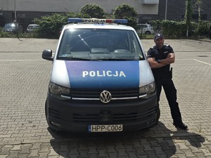policjant stoi przy radiowozie policyjnym