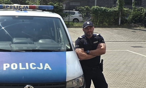 policjant stoi przy radiowozie policyjnym