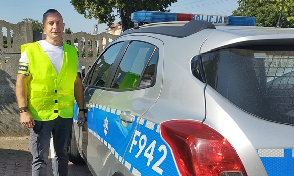 na zdjęciu policjant stoi przy radiowozie