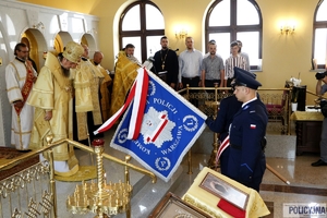 Policjanci klęczą ze sztandarem
