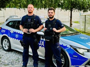 dwaj policjanci stoją przy radiowozie