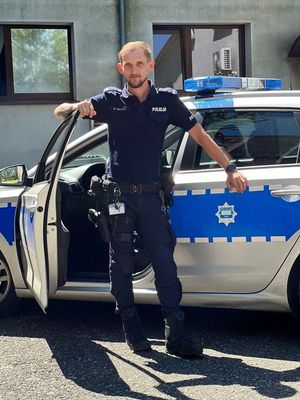 policjant stoi przy radiowozie policyjnym