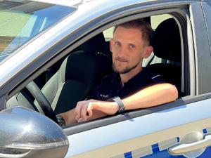 policjant siedzi w radiowozie policyjnym