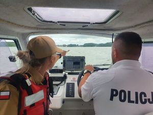 Policjant i funkcjonariuszka straży pożarnej podczas kontrolowania zbiornika wodnego.