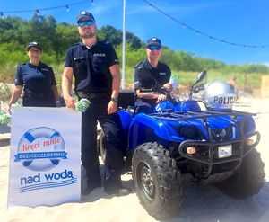 Troje policjantów pozuje do zdjęcia na plaży.