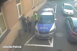 Policjanci wraz z zatrzymanym mężczyzną przy zaparkowanym na ulicy radiowozie